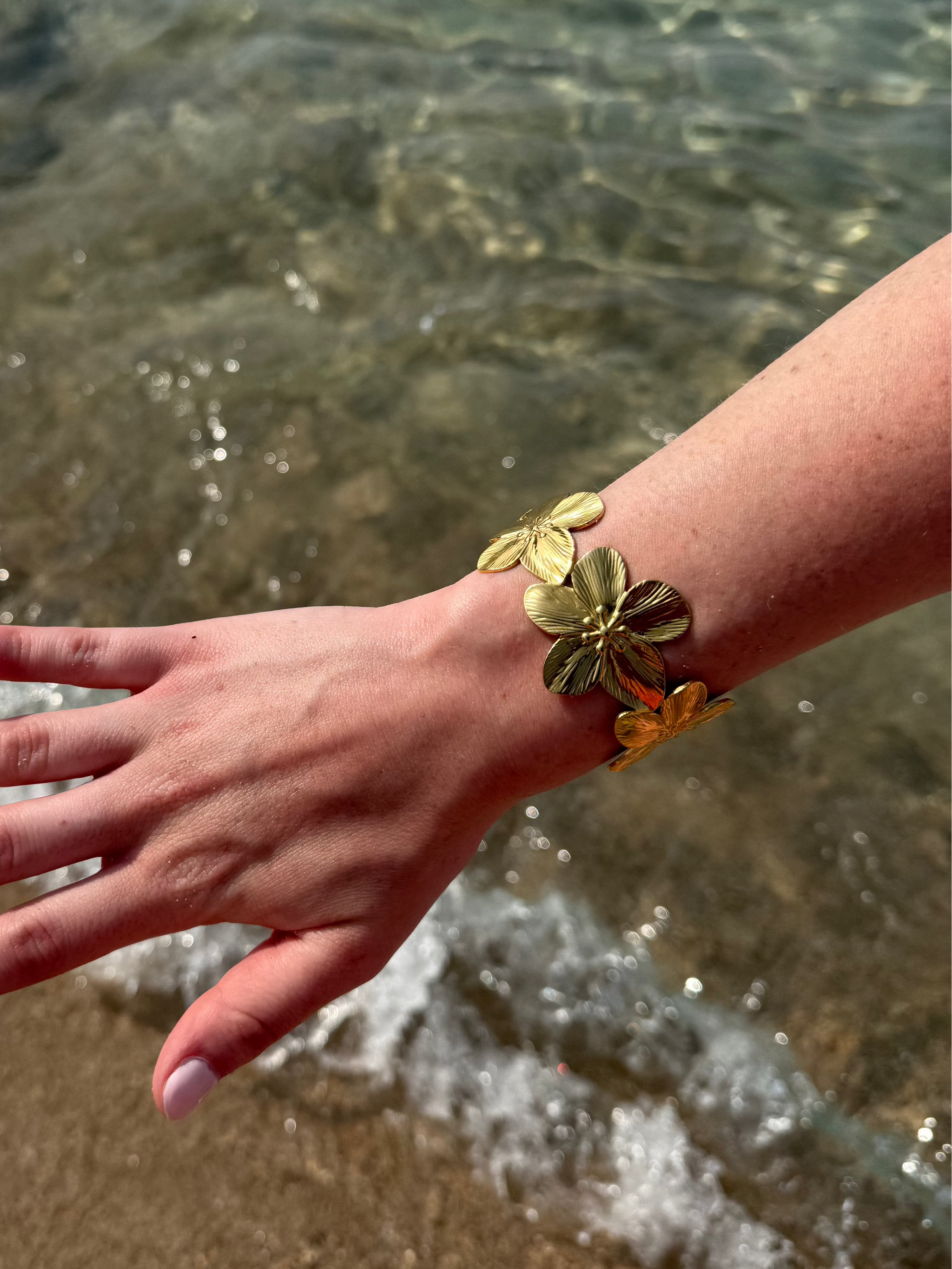 bracelet doré fleurs porté sur la plage