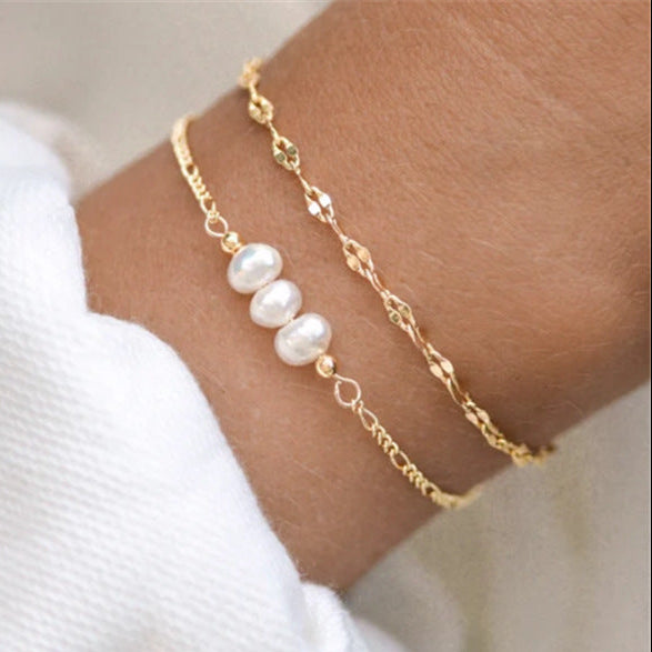 bracelet doré avec trois perles blanches sur un poignet